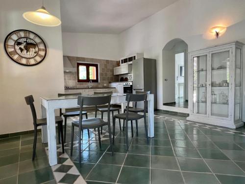a kitchen with a table and chairs and a clock at Villa Peru in Tanaunella