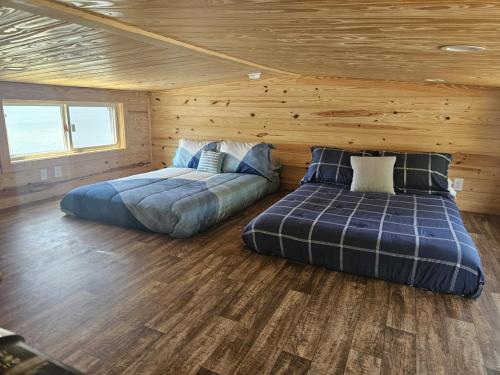 twee bedden in een kamer met houten wanden en houten vloeren bij Lake Front Cottage Paradise in Pittsburg