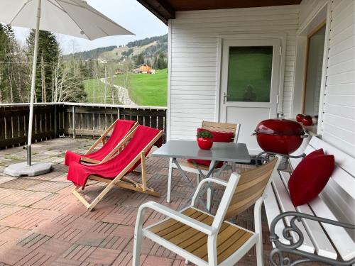 a patio with two chairs and a table and an umbrella at Kleine Ferienwohnung am Rande der Wildnis in Sibratsgfäll