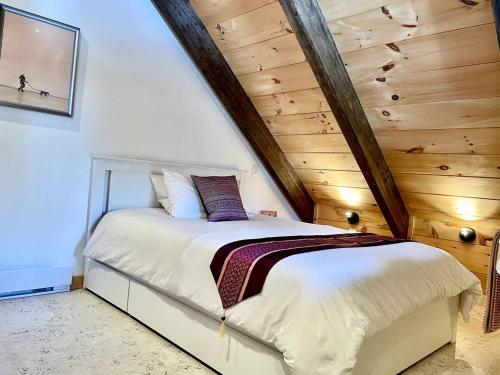 a bed in a room with a wooden ceiling at Enchanting chalet in an oasis of nature [new 2021] in Val-Morin