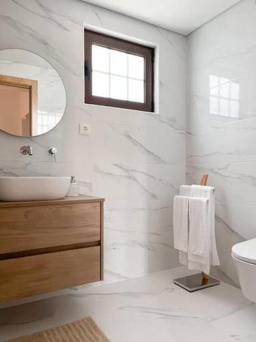 a white bathroom with a sink and a mirror at Casa da Eira by Quantique in Amares