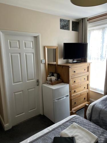1 dormitorio con 1 cama, TV y puerta en Willows Guest House, en Great Yarmouth