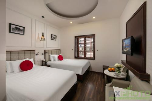 una camera d'albergo con due letti e una televisione di Victory Legend Hotel - In Hanoi Central a Hanoi