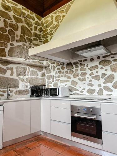 a white kitchen with a stone wall at Casa da Eira by Quantique in Amares