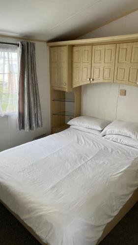 a large white bed in a room with a window at Caravan home Clacton-On-Sea St Osyth in Saint Osyth