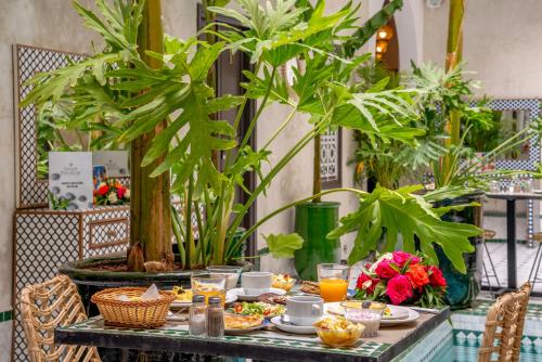 Riad Samir Privilege Boutique Hotel & Spa في مراكش: طاولة عليها طعام ومشروبات بالنباتات