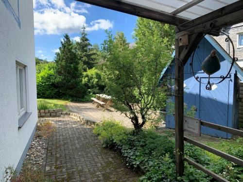 a walkway next to a blue building with a bird on a lantern at Landhaus am Bach in Winterberg-Silbach in Winterberg