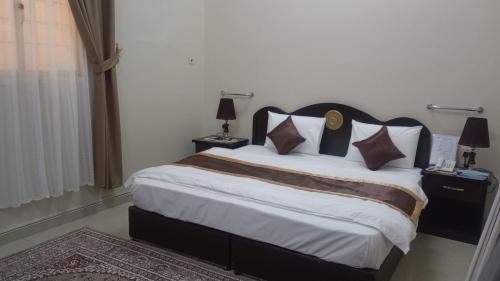 um quarto com uma cama grande com 2 candeeiros e um tapete em العييري للشقق المفروشة االنعيريه 1 em Al Nairyah
