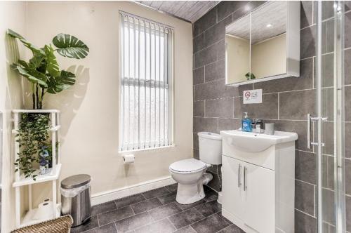 a bathroom with a toilet and a sink and a window at Bright sunny, double bed with garden, TV and Wi-Fi in Leeds