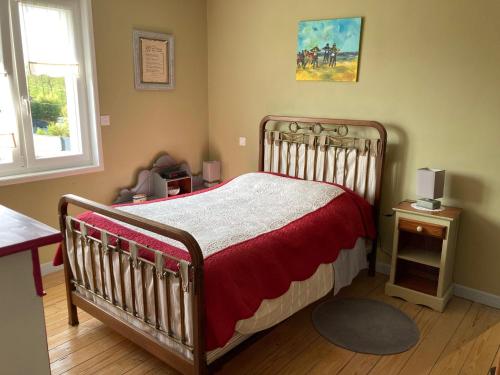 a bedroom with a bed with a red and white blanket at La Source de la Liane in Menneville