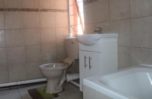 ein Badezimmer mit einem WC, einem Waschbecken und einer Badewanne in der Unterkunft Macum Guesthouse in Roodepoort