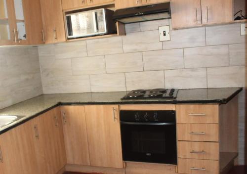 a kitchen with wooden cabinets and a black stove top oven at Macum Guesthouse in Roodepoort
