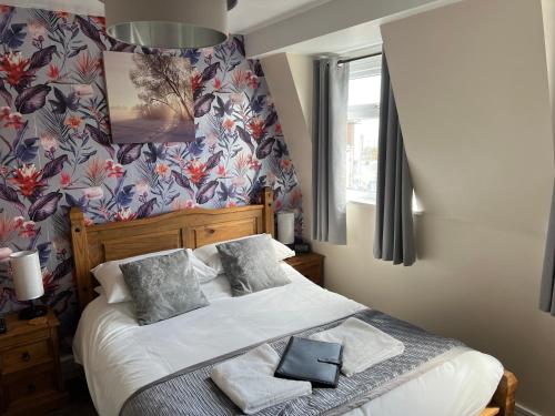 a bedroom with a bed with a floral wallpaper at Willows Guest House in Great Yarmouth
