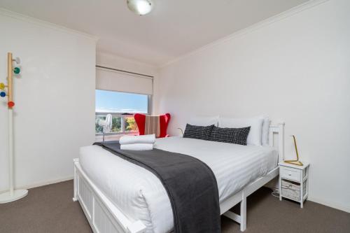 a white bedroom with a large bed and a window at Spacious and Cosy Apt with Great Views in Braddon - Hosted by CanStay in Canberra