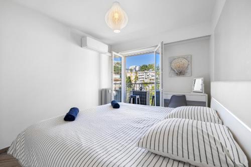 a white bedroom with two beds and a window at Le Hammam in Nice