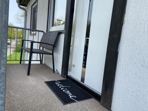 a balcony with a chair and a welcome mat at Ferienwohnung am Erbacher Mümlingufer in Erbach im Odenwald