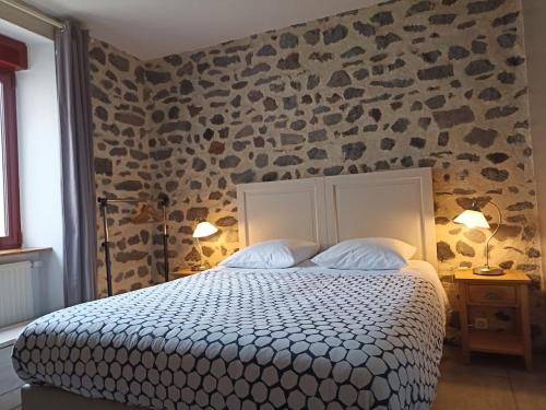 a bedroom with a bed and a stone wall at La Maison de Lili in Loudes
