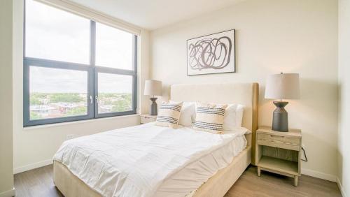 a white bedroom with a bed and a window at Landing at Logan Apartments - 1 Bedroom in Logan Square in Chicago