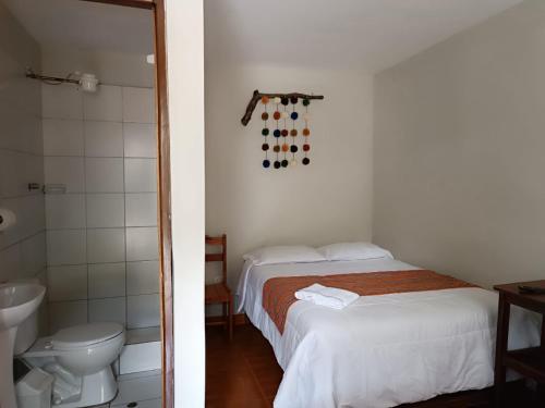 a bedroom with a bed and a bathroom with a toilet at Hospedaje Quillabamba in Santa Teresa