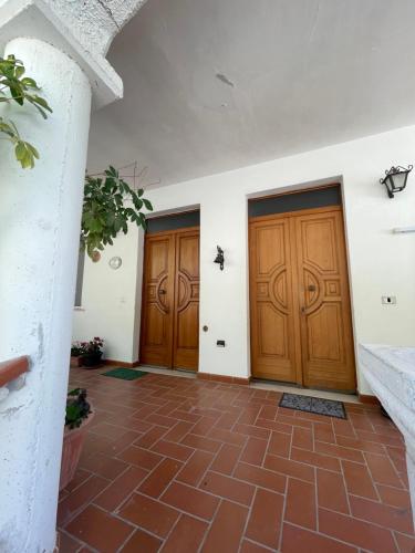 two wooden doors in a room with a brick floor at La Villa del Pixus in Pisciotta
