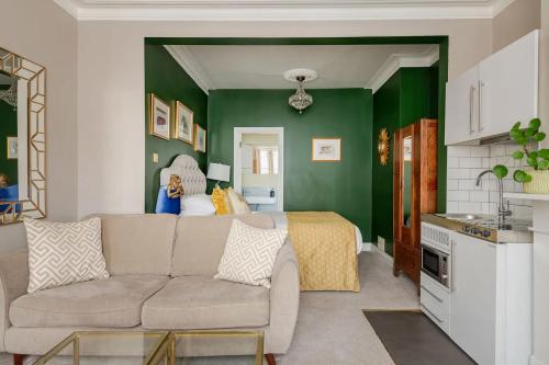 a living room with a couch and a green wall at Deco Studio: King bed, kitchenette, stylish & comfortable in Brighton & Hove
