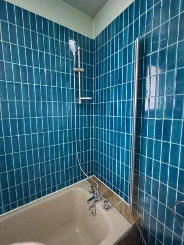 La salle de bains est pourvue de carrelage bleu, d'une baignoire et d'une douche. dans l'établissement Green Nest - Metro line 7, à La Courneuve