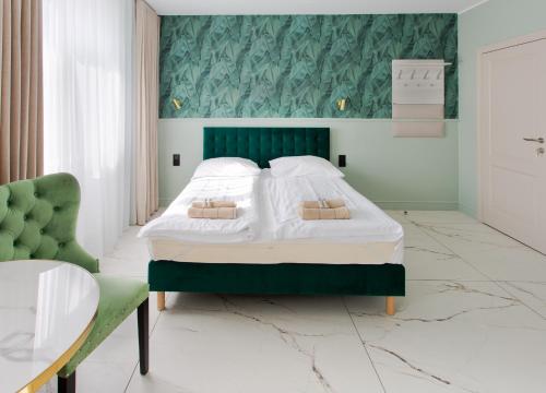 a bedroom with a large bed with a green headboard at Meduza Sopot in Sopot