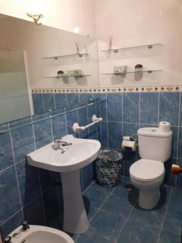 Baño de azulejos azules con aseo y lavamanos en Apartamento zona de los osos, en Santander