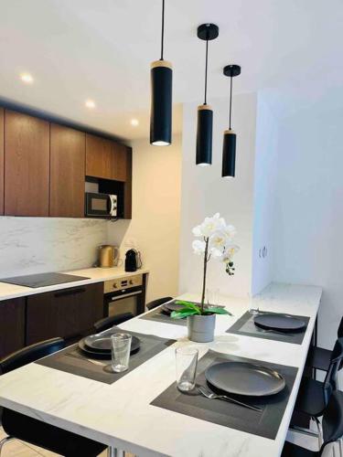 d'une cuisine avec une table avec des assiettes et des fleurs. dans l'établissement Carré Or - Standing Hyper centre plage 2 min, à Saint-Raphaël