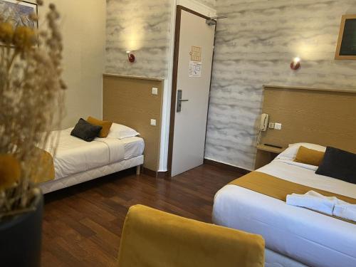 a hotel room with two beds and two chairs at Hôtel Abalone - Centre Gare in Nîmes