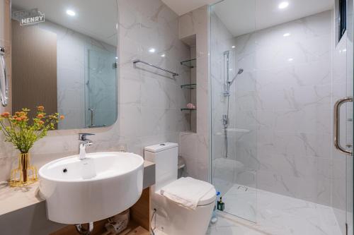 a white bathroom with a sink and a shower at Son&Henry Zenity District 1 in Ho Chi Minh City