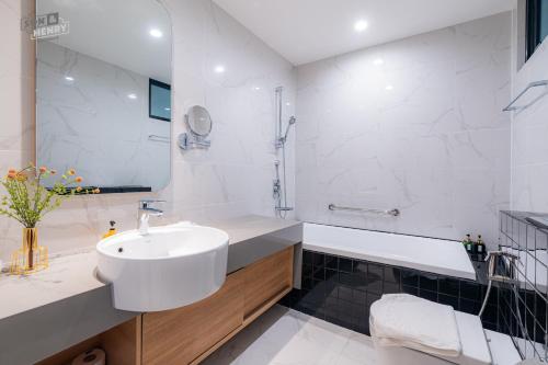 a white bathroom with a sink and a tub at Son&Henry Zenity District 1 in Ho Chi Minh City