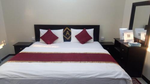um quarto com uma cama com almofadas vermelhas e pretas em العييري للشقق المفروشة النعيريه 4 em Al Nairyah