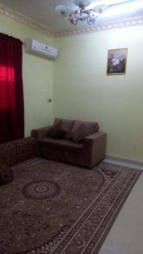 um sofá castanho numa sala de estar com um tapete em العييري للشقق المفروشة النعيريه 4 em Al Nairyah