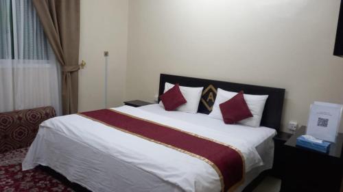 um quarto com uma cama grande e almofadas vermelhas em العييري للشقق المفروشة النعيريه 4 em Al Nairyah