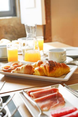 a table topped with two plates of pastries and orange juice at Solar das Bouças by Quantique in Amares