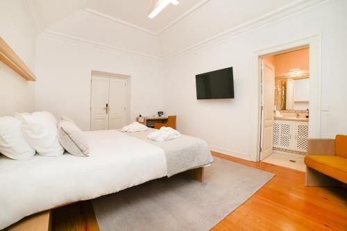 a white bedroom with a bed and a television at Solar das Bouças by Quantique in Amares