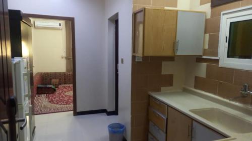 uma cozinha com um lavatório e uma porta para um quarto em العييري للشقق المفروشة النعيريه 4 em Al Nairyah