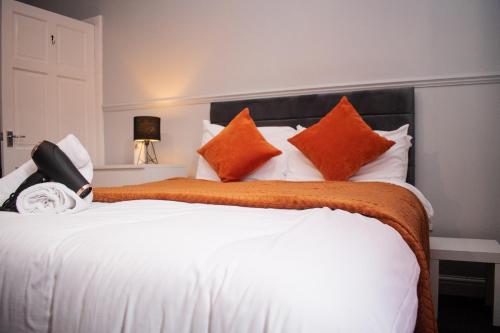 a bedroom with a large white bed with orange pillows at Stylish 1 Bedroom Flat Newcastle in Old Walker