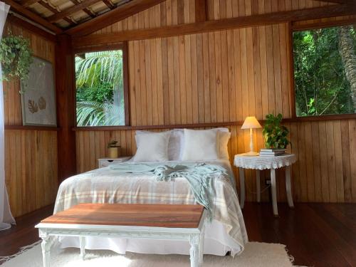 1 dormitorio con 1 cama con mesa y 2 ventanas en Glamping Casa D'Arvore Camburizinho, en São Sebastião