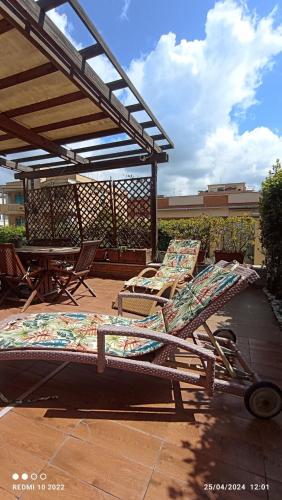 a patio with two lounge chairs and a pergola at La Casetta 2 -10 min Aeroporto e spiaggia in Fiumicino