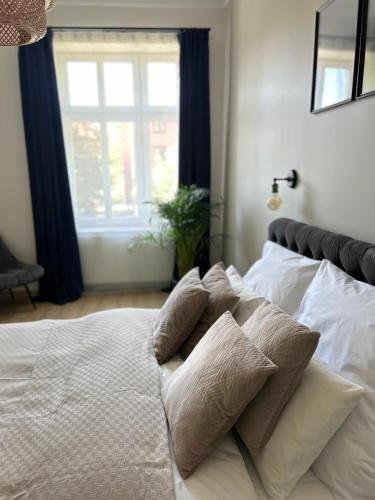 a white bed with pillows on it with a window at Apartament No. 5 City Center in Świdnica