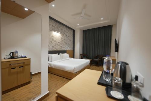 une chambre d'hôtel avec un lit blanc et une cuisine dans l'établissement Xenious Micro, Amritsar, à Amritsar