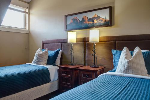 a bedroom with two beds and two lamps in it at Panoramic Mountain View Condo in Canmore