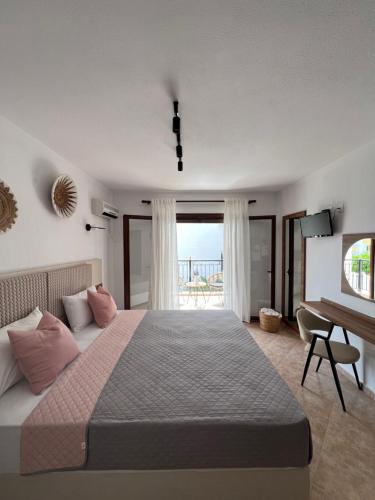 sypialnia z dużym łóżkiem, biurkiem i oknem w obiekcie Pantheon w mieście Skiatos