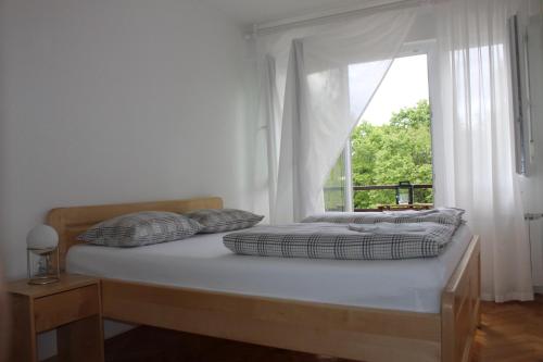 a bed with two pillows and a window in a room at Apartman Black River in Plitvička Jezera