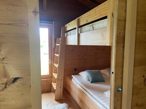 Łóżko piętrowe w drewnianym pokoju z oknem w obiekcie Le Rucher Mirabelle w mieście Coeuve