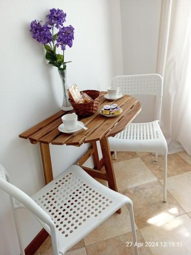 einen Holztisch mit einer Vase aus Blumen und zwei Stühlen in der Unterkunft IL GIARDINO in La Spezia