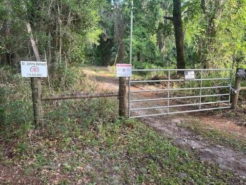 a fence on a dirt road with signs on it at St Johns River Retreat Unit 1 in Crescent City