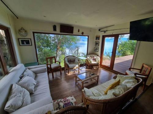 ein Wohnzimmer mit einem Sofa und Stühlen sowie einem großen Fenster in der Unterkunft Casa a orilla del lago in Pucón